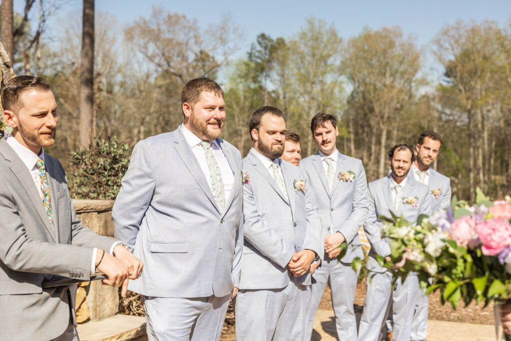 Groom smiling at bride walking down the aisle