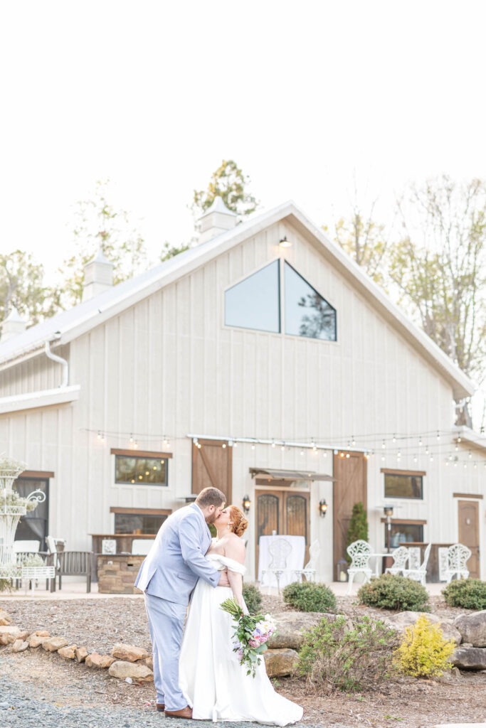 Bride and Groom kisses in front of Lavender Oaks Farm main barn
